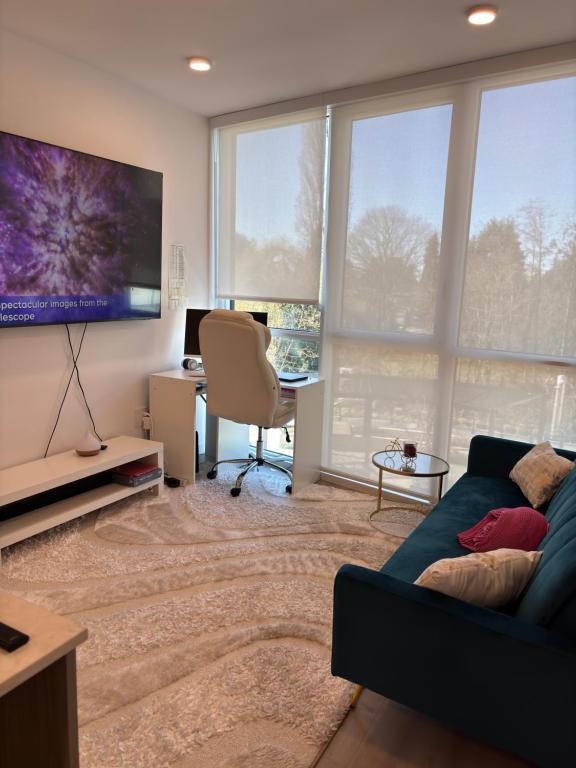 a living room with a couch and a desk and windows at Executive 2 bed luxury Suit in Surrey