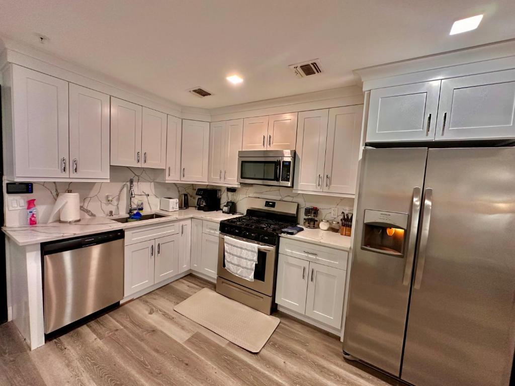a kitchen with white cabinets and a stainless steel refrigerator at The Cozy Suite - 1BR with Free Parking in Paterson