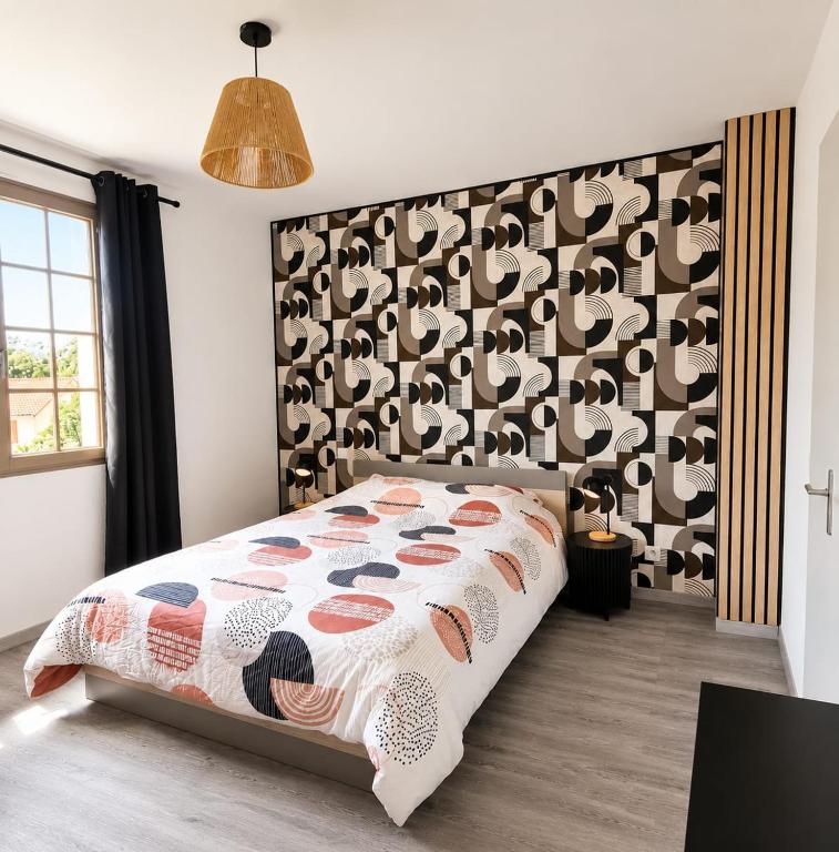 a bedroom with a bed with a patterned wall at Ambre in Bény