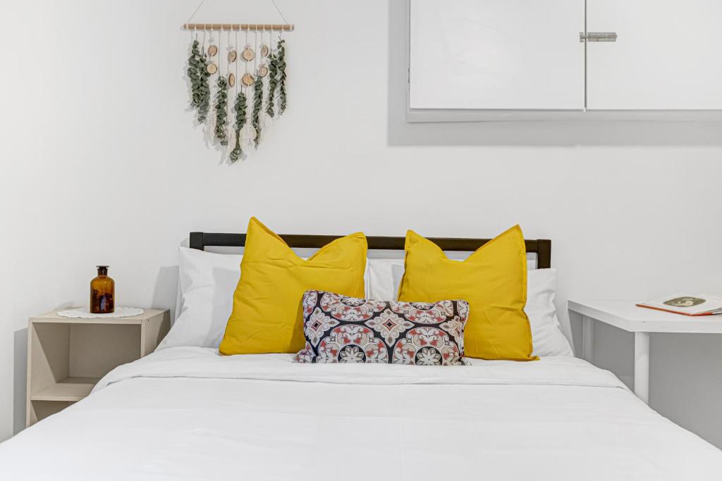 a bedroom with a white bed with yellow pillows at Bright 2BR Basement Apartment with Free Parking in Toronto