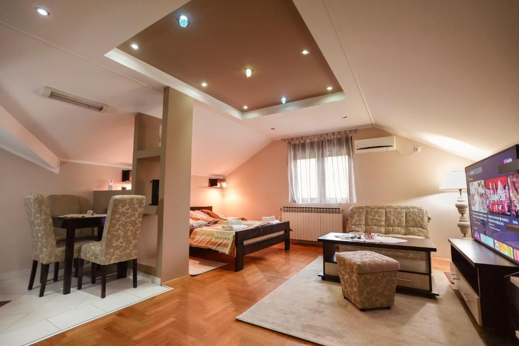 a living room with a dining table and a room with a television at D apartmani in Sremska Kamenica