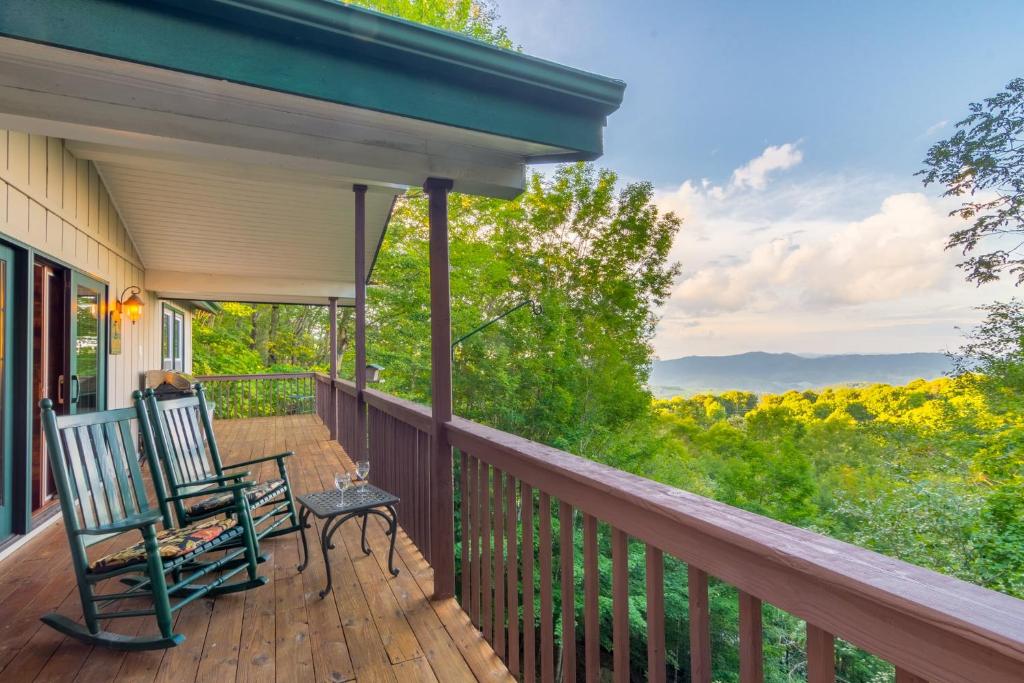 a porch with two chairs and a view of the woods at Mountain Stay Chalet in Beech Mountain