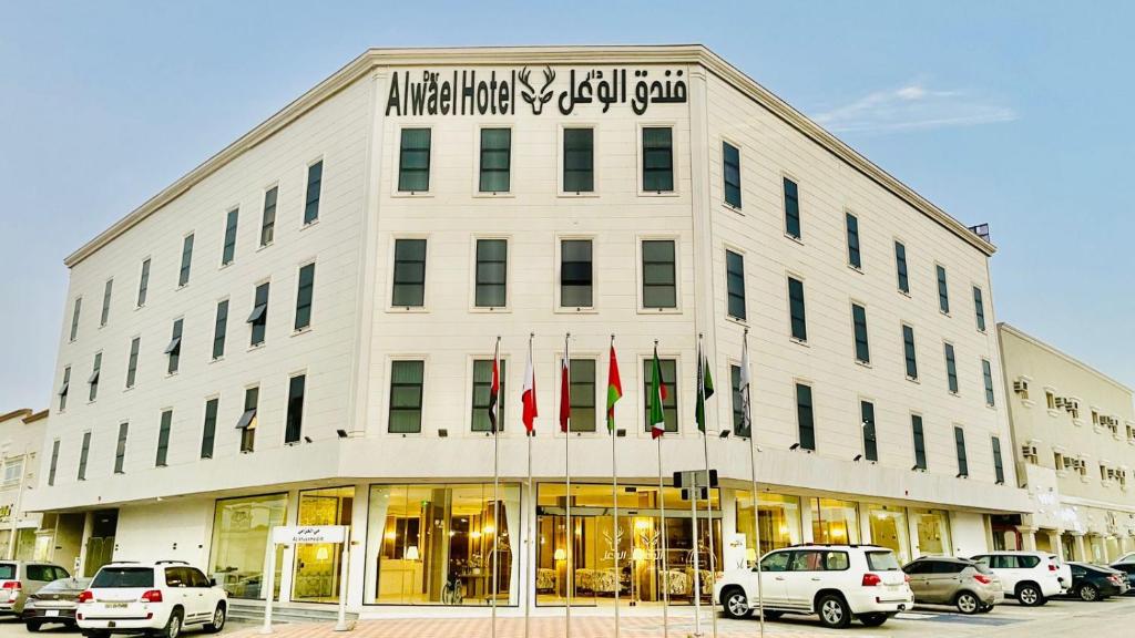 a white building with cars parked in front of it at فندق الوعل بالخفجى in Khafji