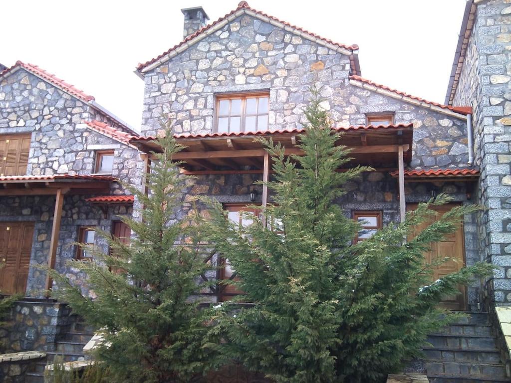 kamienny dom z dwoma drzewami przed nim w obiekcie Vitina Stone House w mieście Vytina