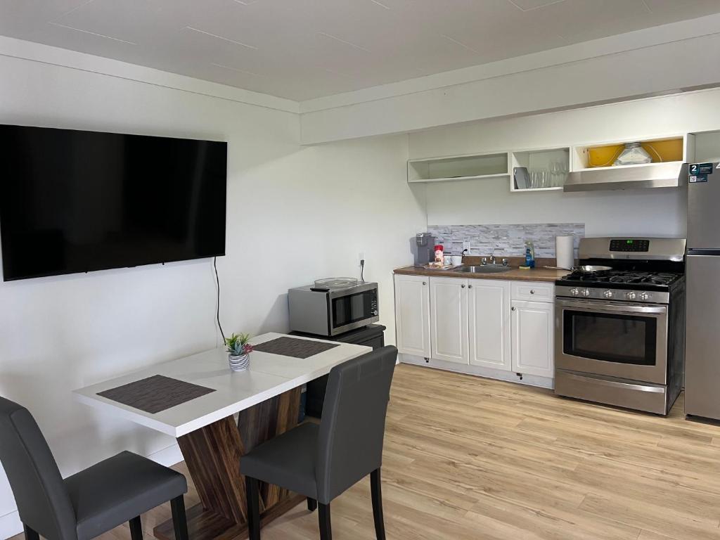 a kitchen with a table and a television on the wall at Stampeder Inn in Williams Lake