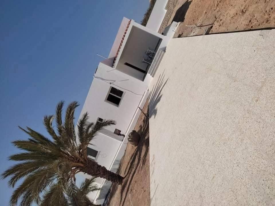 a white building with a palm tree next to it at Dar saber in Sfax