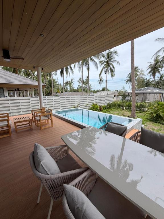 a patio with a table and chairs and a swimming pool at Wave Villa New 2BR Pool Villa in Ko Phangan
