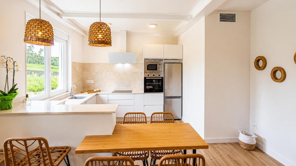 a kitchen with a wooden table and chairs at O Retiro da Costa Galitrips in Muxia
