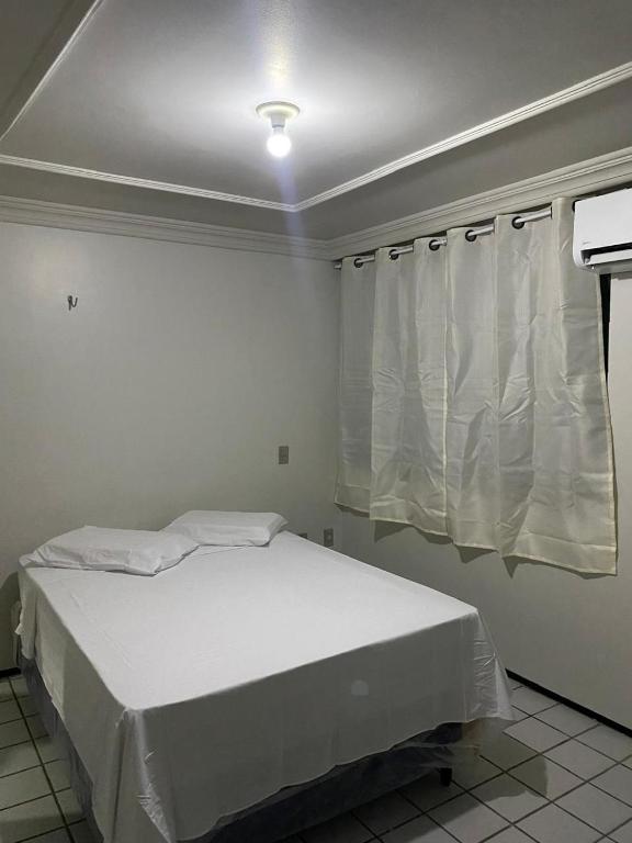 a white bed in a room with a window at Pousada recanto nordestino in Caucaia