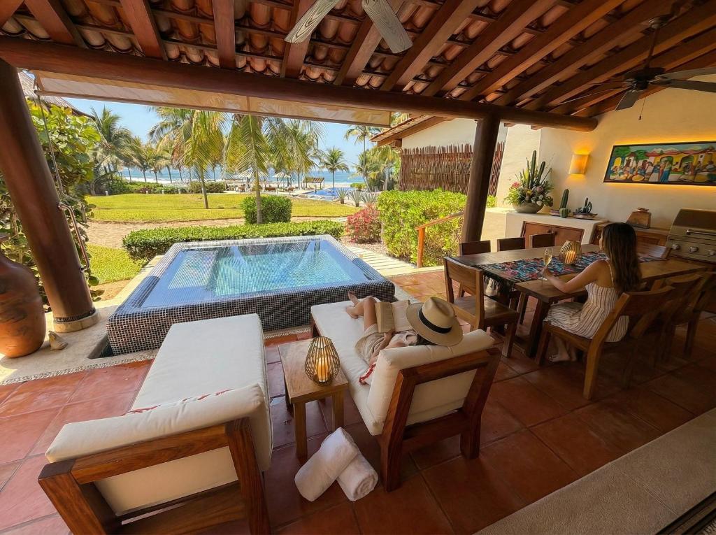 a woman sitting at a table next to a swimming pool at Residences at Las Palmas in Zihuatanejo