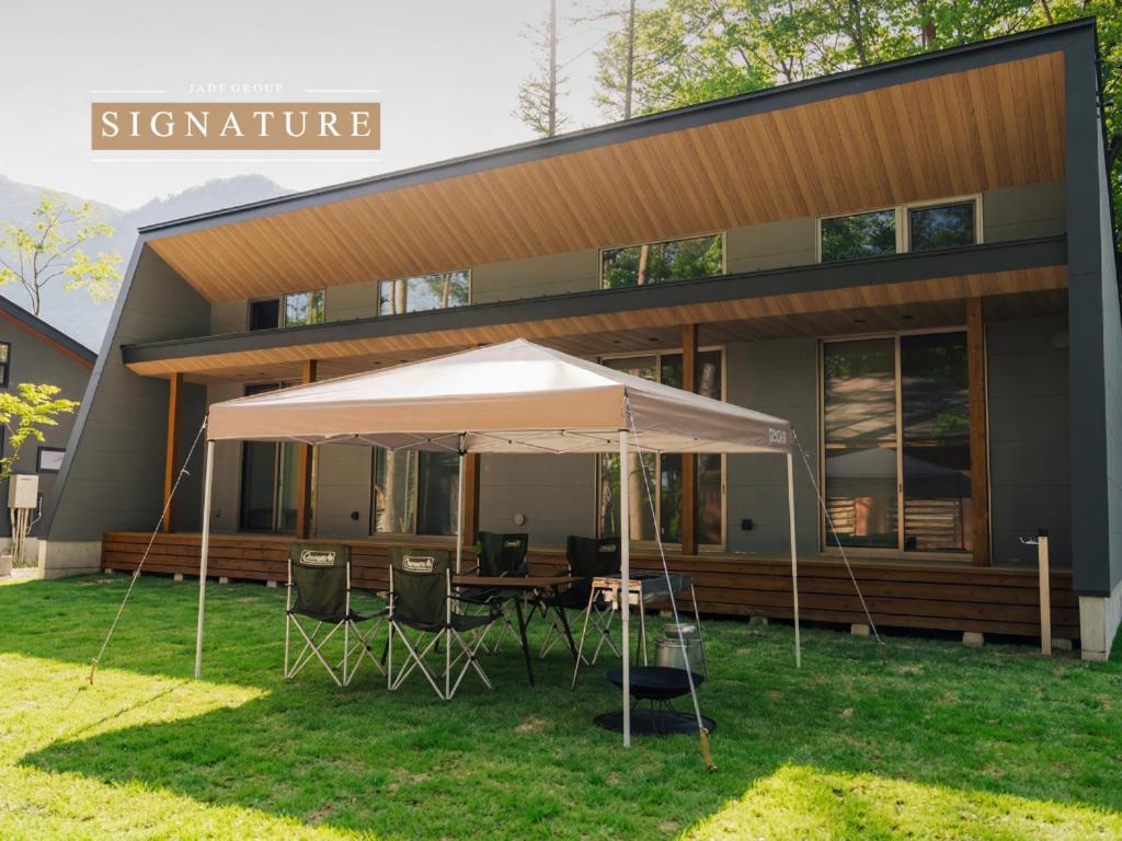 ein Tisch mit einem Sonnenschirm vor einem Haus in der Unterkunft Mimi Hakuba by Jade Villa in Hakuba