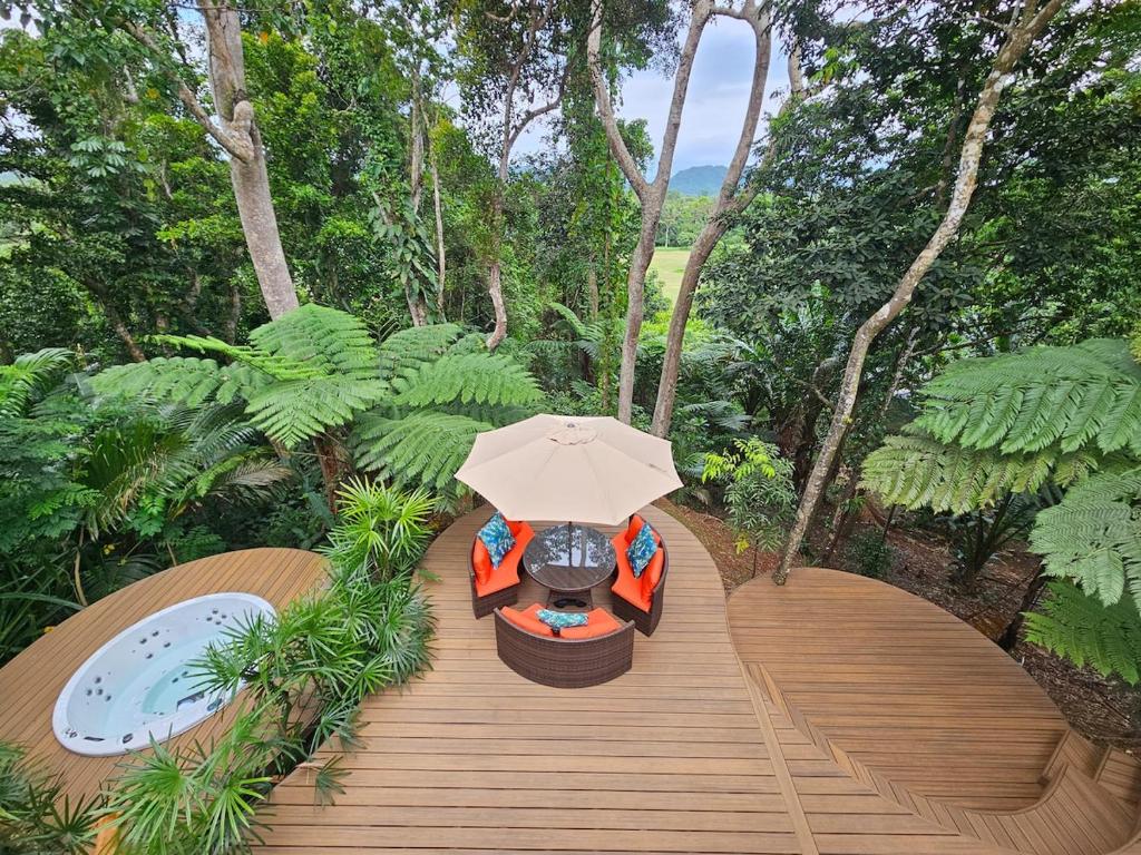 a wooden walkway with a bench and an umbrella at Seven on the Hillside in Pacific Harbour