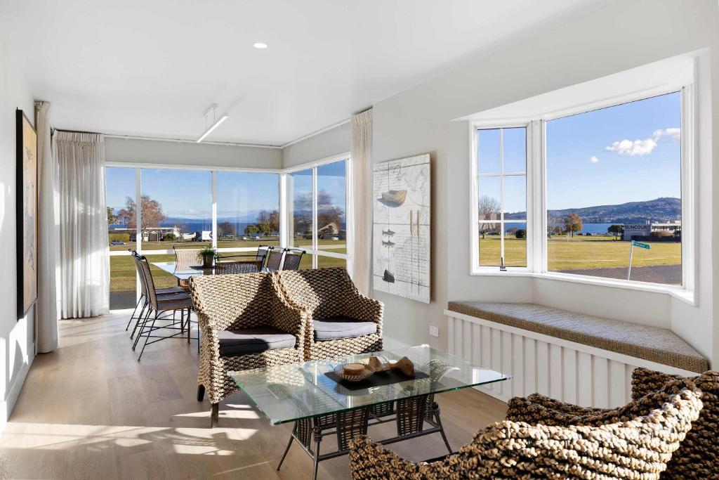 a living room with a table and chairs and windows at Fletcher House Sleeps 18 Location Views in Taupo