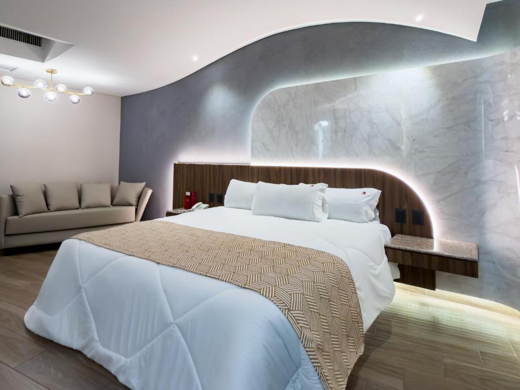 ein Schlafzimmer mit einem großen weißen Bett und einer Couch in der Unterkunft Hotel Via La Villa in Mexiko-Stadt