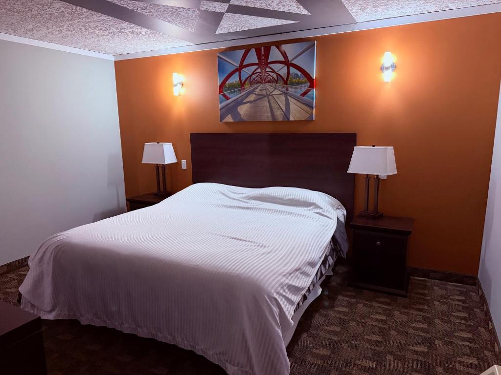 ein Schlafzimmer mit einem großen weißen Bett und zwei Lampen in der Unterkunft Premium Inn & Suites in Calgary