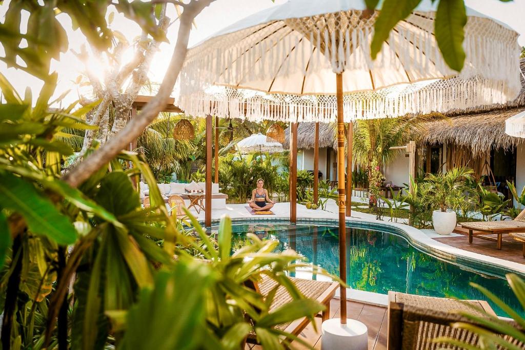 a woman is sitting by a pool at a resort at Luana Lombok in Selong Belanak