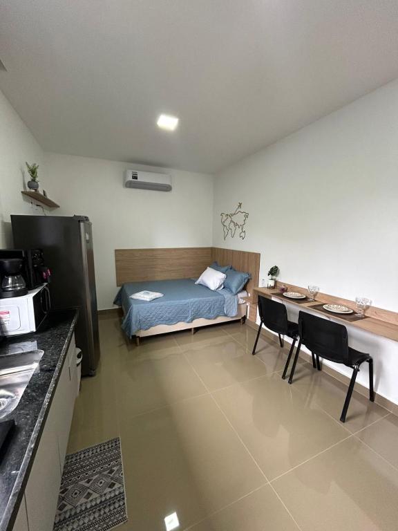 a bedroom with a bed and a table and chairs at Studio CG Tingui 1 in Estação Inhoaíba