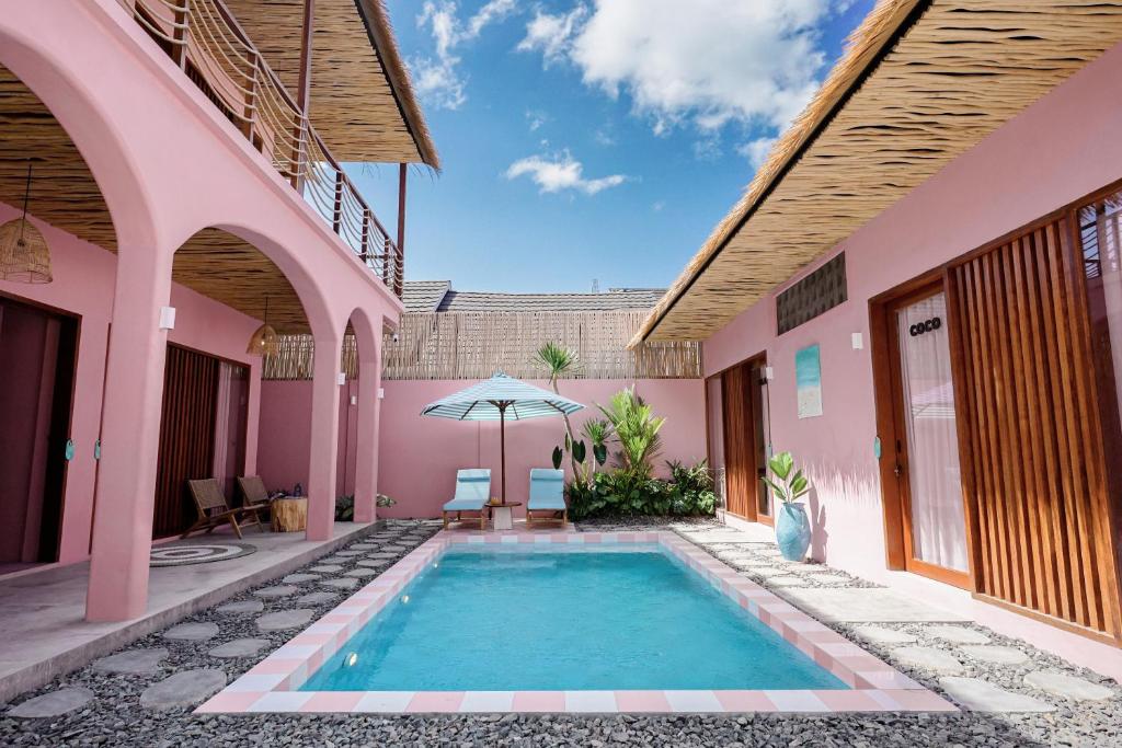a swimming pool in the courtyard of a pink house at Hyde Boutique Hotel in Kuta Lombok