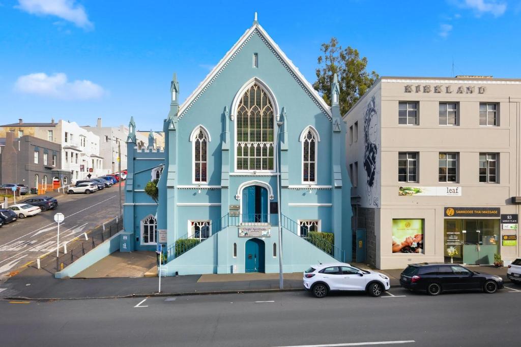 a blue church with cars parked in front of it at Chapel On Moray - Apartment in Dunedin