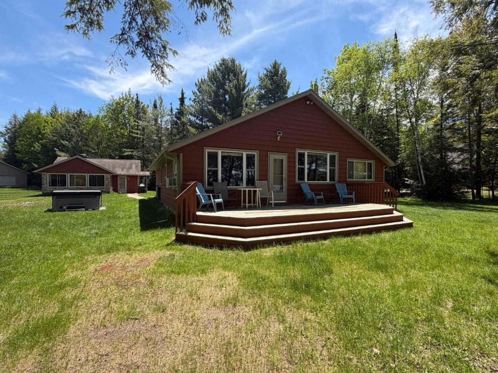 a small red house with a porch and a deck at Watermelon Retreat in Three Lakes