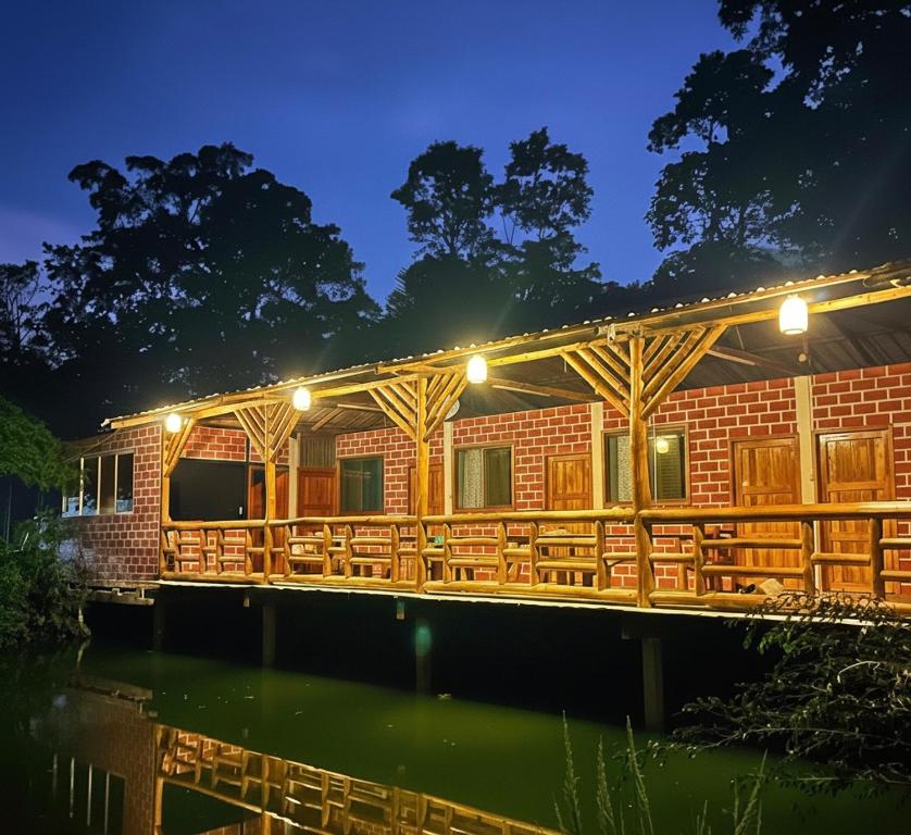 a building with tables and chairs on the water at night at Sisa Lodge in Tena
