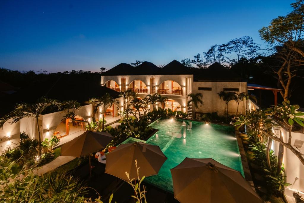 an exterior view of a house with a swimming pool with umbrellas at Casa Nova Villa Uluwatu in Uluwatu
