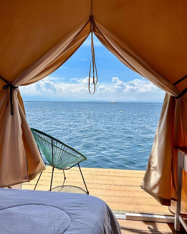 a bed and a chair sitting on a dock with the ocean at Reef Resort - Mount Apo View Unit B1 in Kaputian