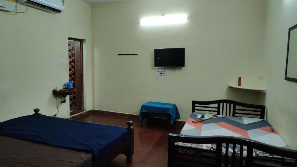 a room with two beds and a tv on the wall at The beach light in Auroville