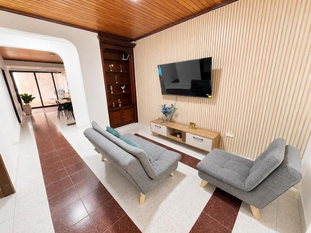 a living room with two chairs and a flat screen tv at Urban House in Florencia