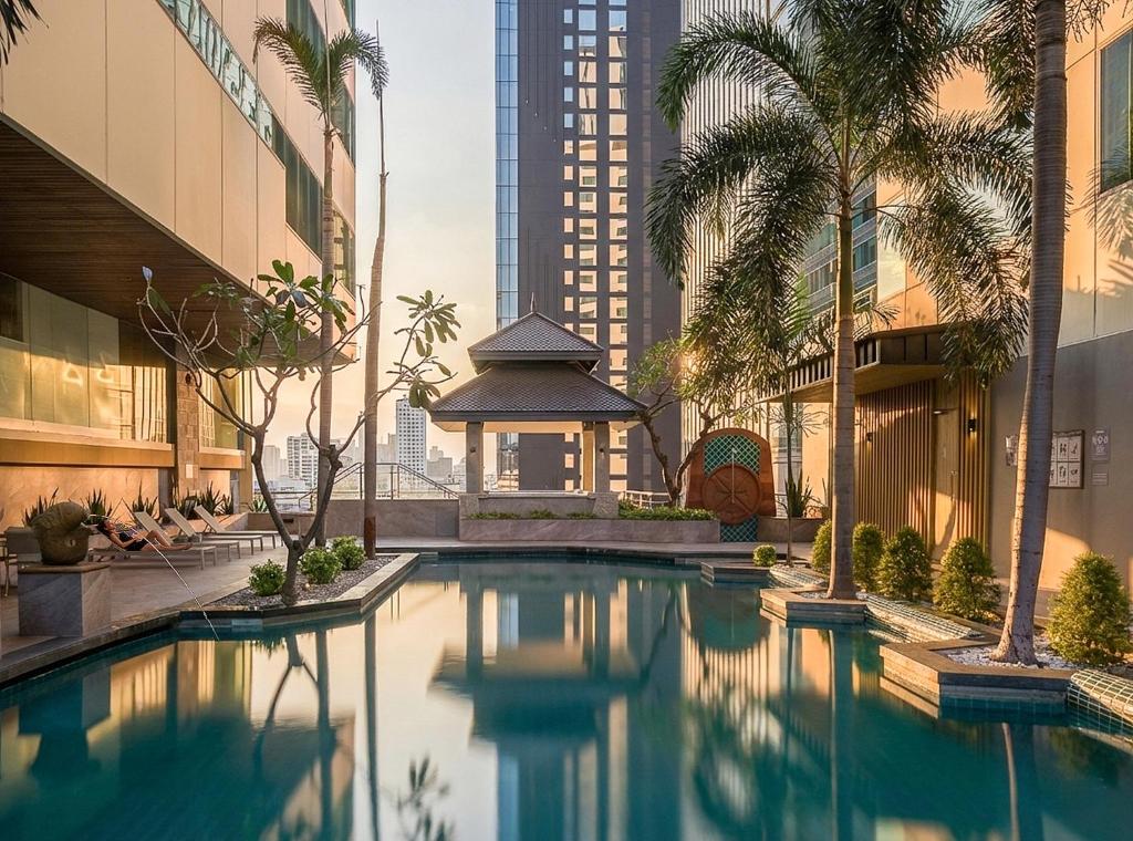 a swimming pool with palm trees and a gazebo at Jasmine City Hotel Asoke Bangkok in Bangkok