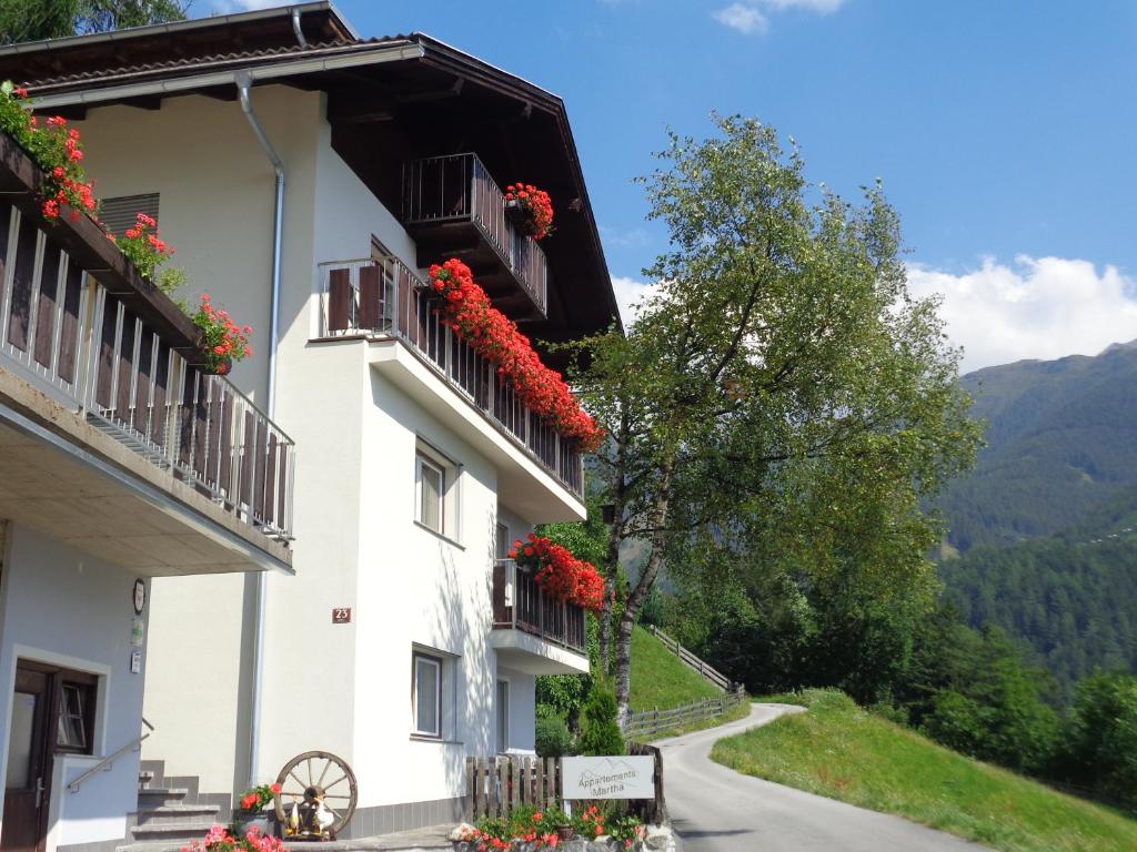 ein Gebäude mit roten Blumen auf Balkonen auf einer Straße in der Unterkunft Appartements Martha in Matrei in Osttirol