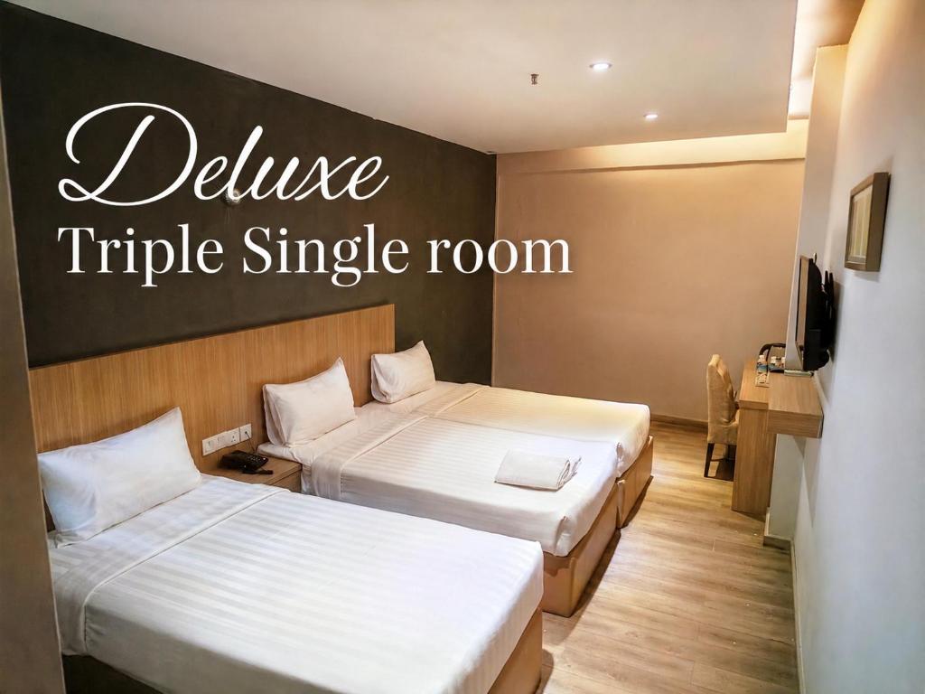 a hotel room with two beds and a sign that readsuce triple single room at Hotel 99 Kuala Lumpur City in Kuala Lumpur