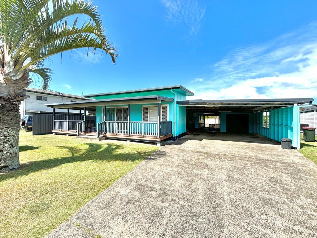 a blue house with a palm tree in front of it at Sunshine on Heath -Pet Friendly in Evans Head