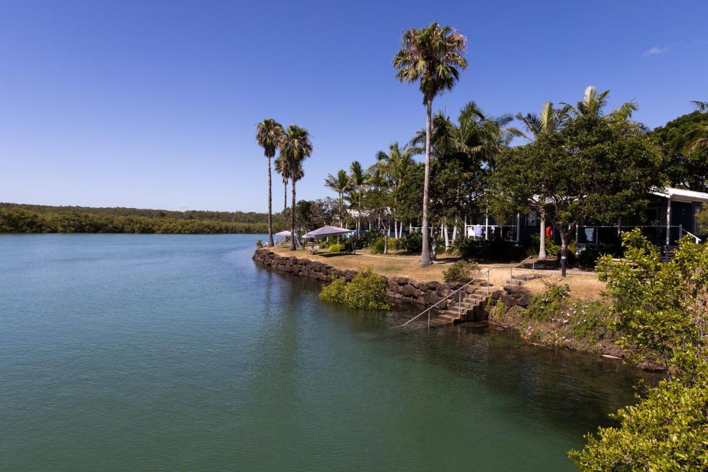 a river with palm trees on the side of it at Reflections Brunswick Head - Holiday Park in Brunswick Heads