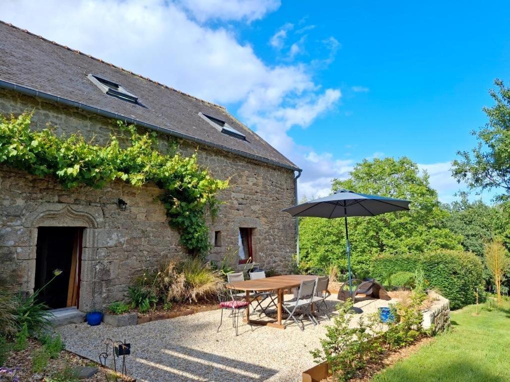 a table with an umbrella next to a building at L'abri de la chouette in Langonnet