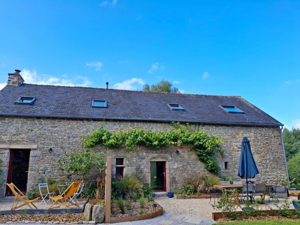 an old stone cottage with a patio and an umbrella at Le refuge des oiseaux in Langonnet
