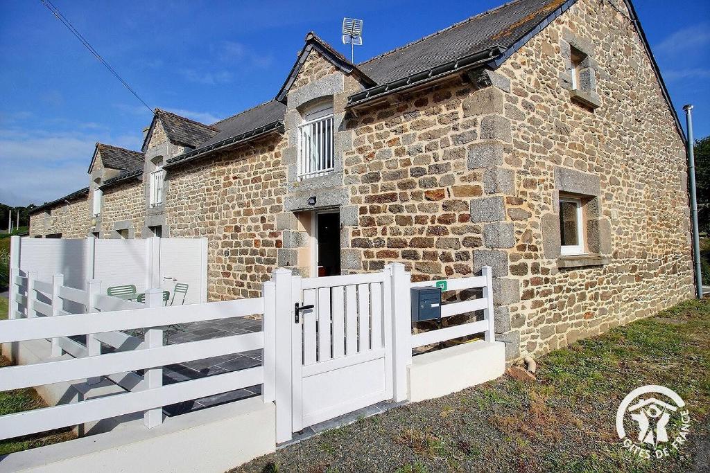 a brick house with a white gate and fence at Le clos rucharet in Saint-Carreuc
