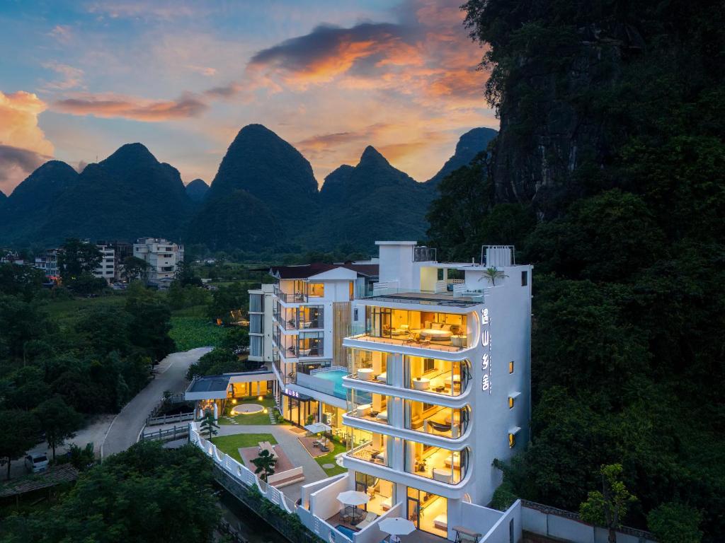 a building with lights on in front of mountains at Yulonghe Yushan Country Hotel in Yangshuo