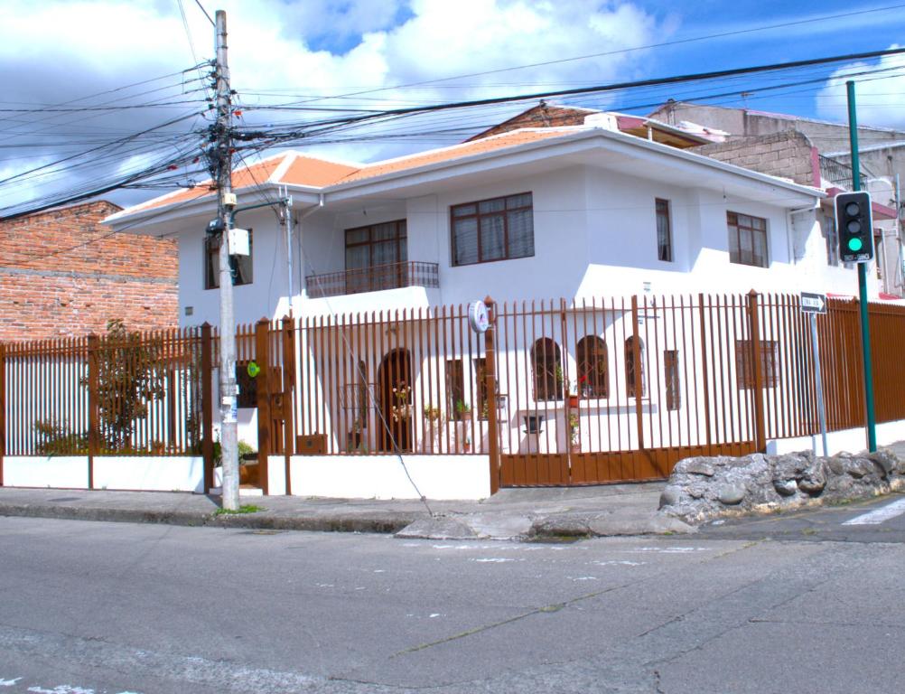 a white house with a fence and a traffic light at Casa Luck Hosting in Cuenca