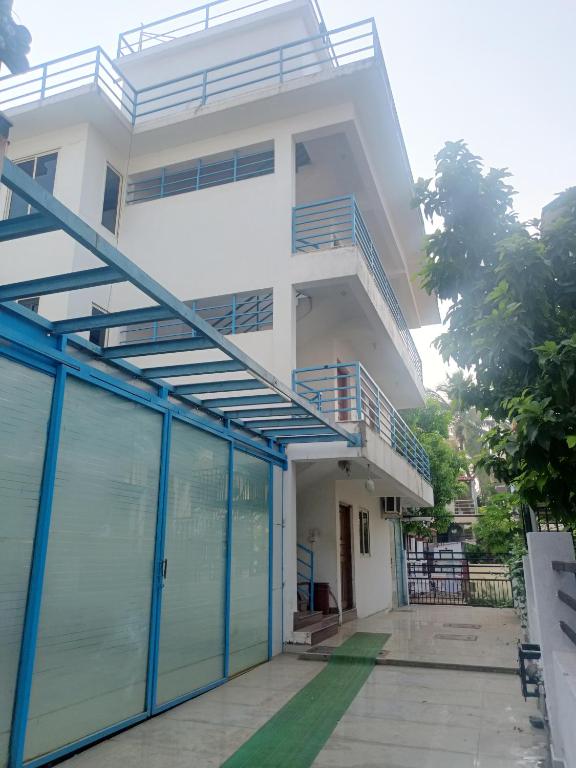 a white house with blue doors in front of it at Guest House Sai Leela in Chicalim