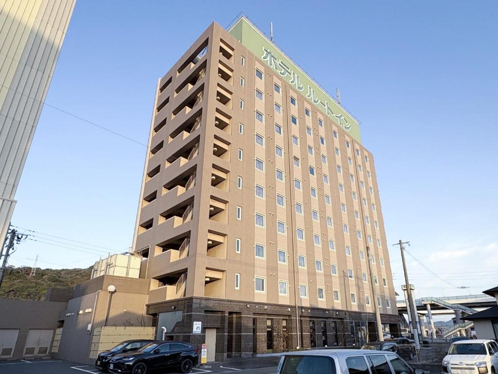 a hotel building with cars parked in a parking lot at Hotel Route-Inn Kanda Ekimae in Kanda