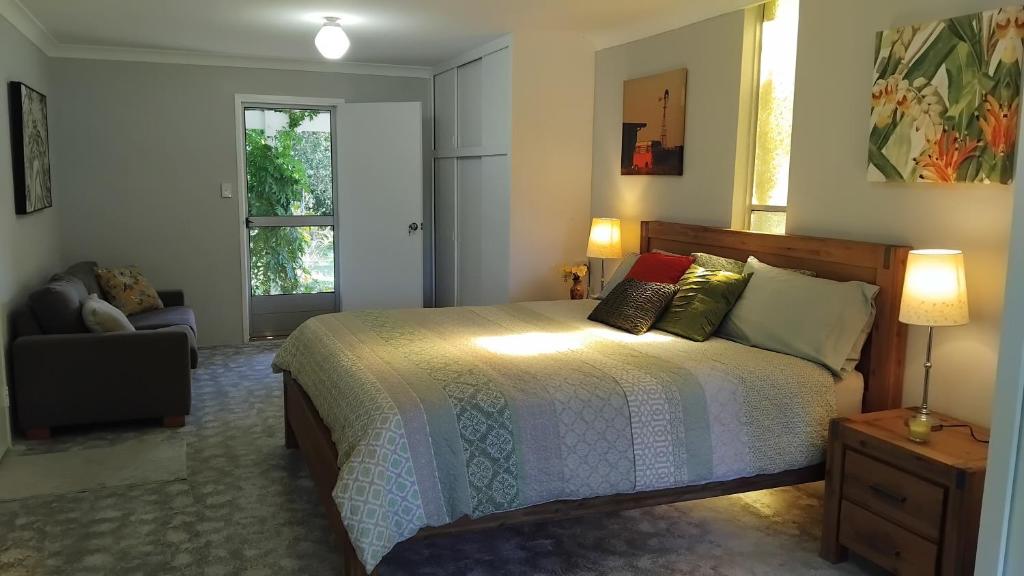 a bedroom with a bed and a chair and a window at King Bed on Mid North Coast 8 mins A1 in Valery