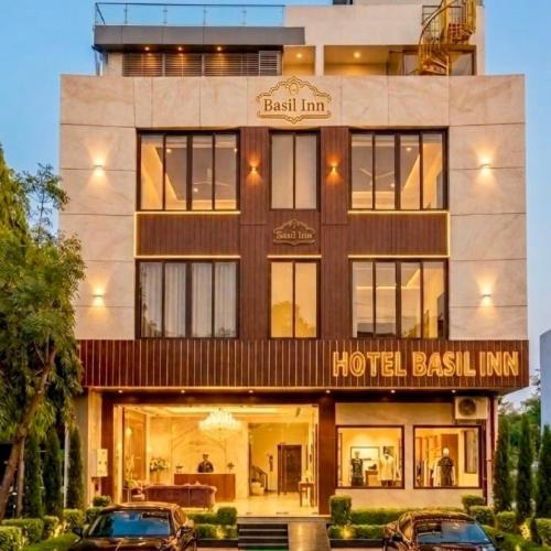 a hotel with two cars parked in front of it at Hotel Basil Inn in Ujjain