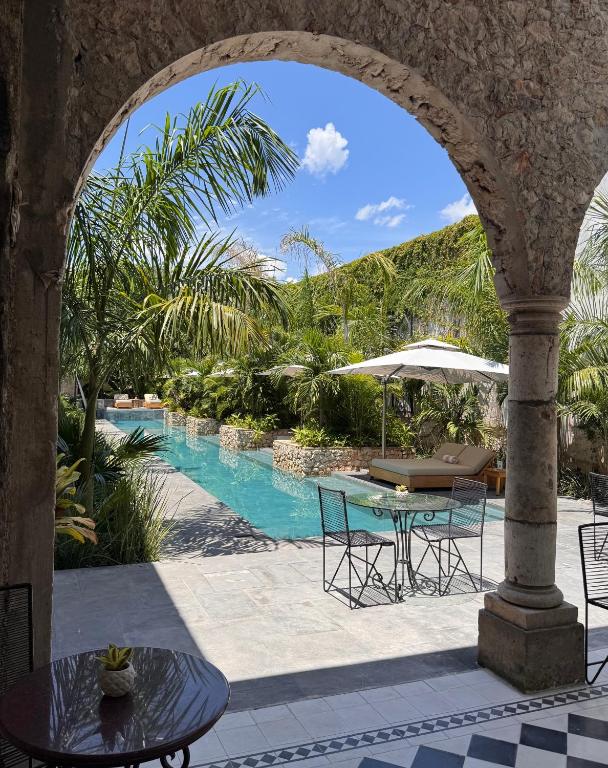 an archway with a table and chairs and a swimming pool at Ontico Urban Design Hotel in Mérida
