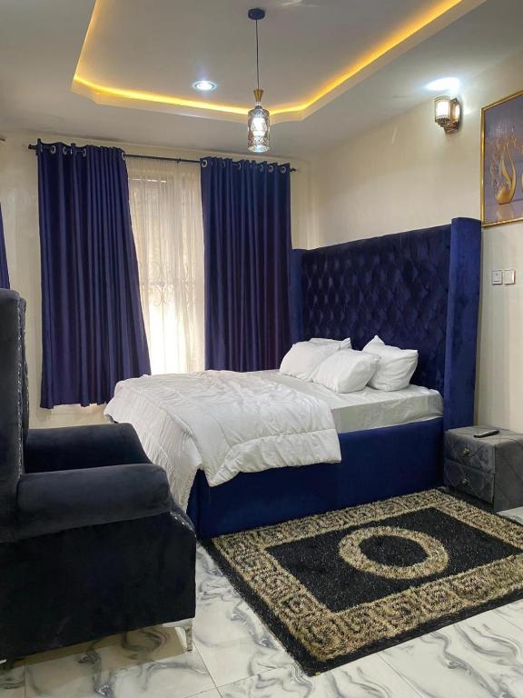 a bedroom with a bed with a blue headboard and a chair at Starlight Homes in Asaba