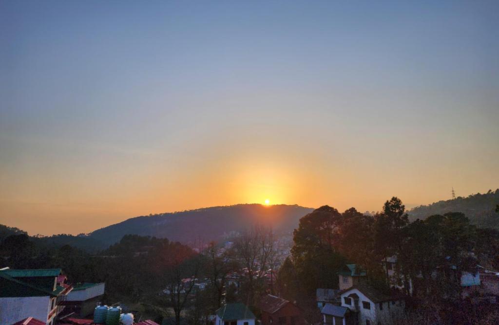 a sunset on top of a mountain in a city at The White Orchid Dalhousie in Dalhousie