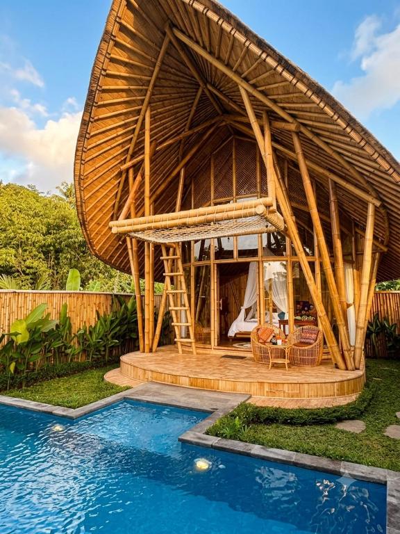 a house with a thatched roof next to a pool at Bamboo Garden Villa Sidemen - Private Pool & Nature View in Selat