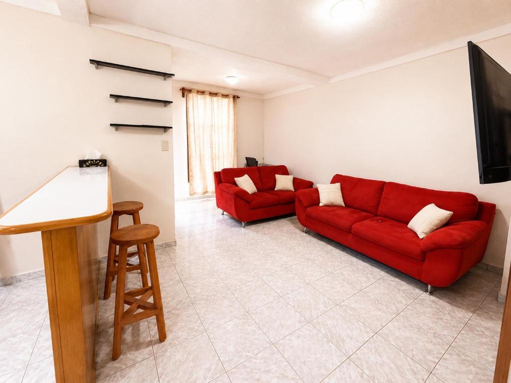 a living room with two red couches and a flat screen tv at Gosen Stays in Antiguo Cuscatlán