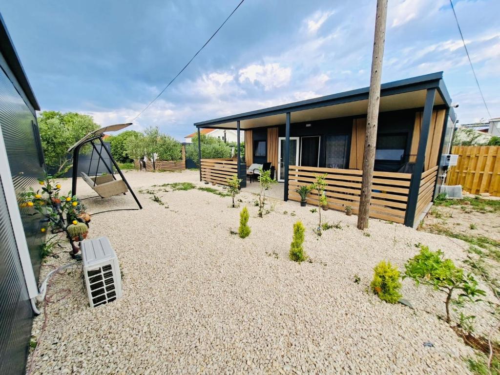 a house with a gravel yard in front of it at Sea Mobile Home in Sukošan