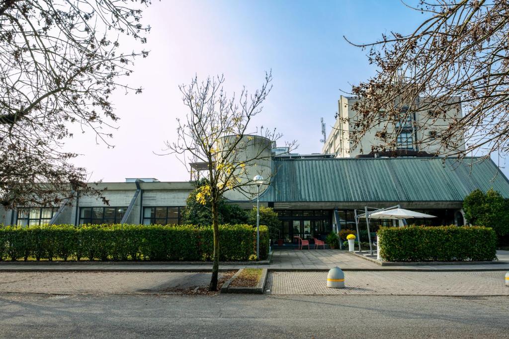 a building with a green roof and a tree at Hotel Cavallino in Faenza